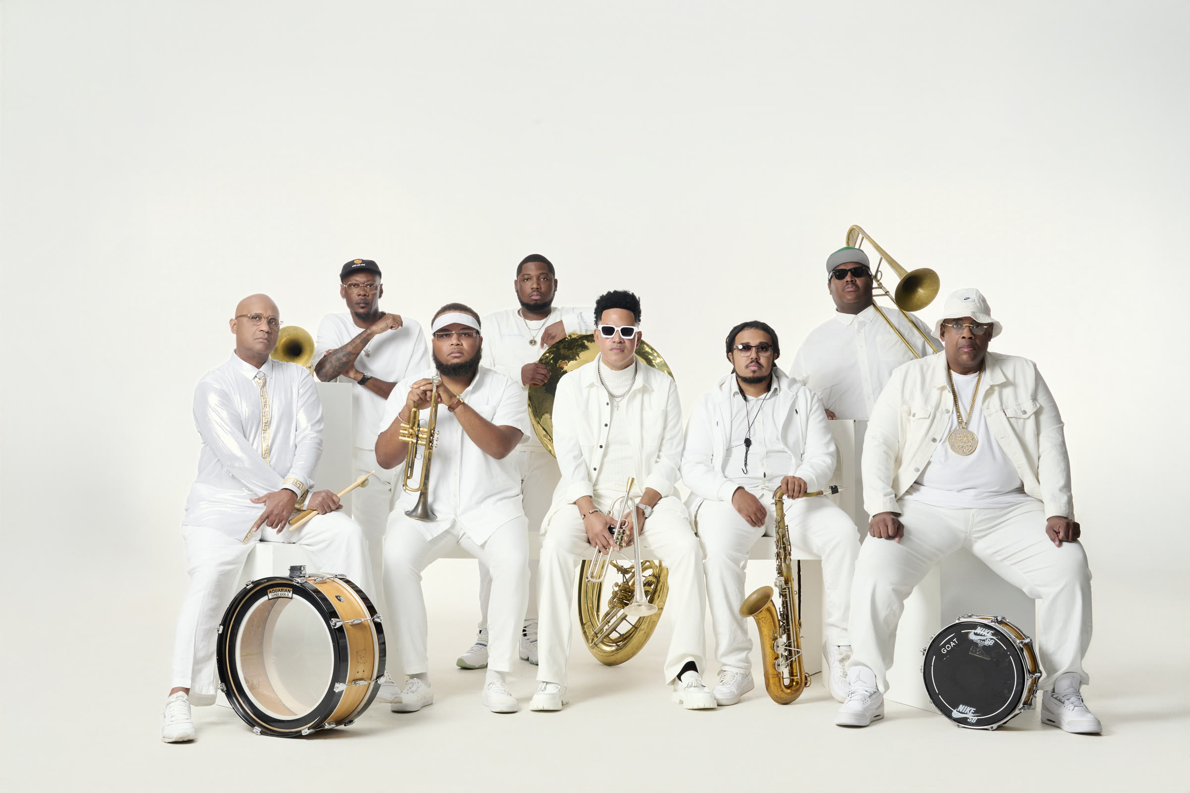 The Soul Rebels standing together in white with their brass instruments