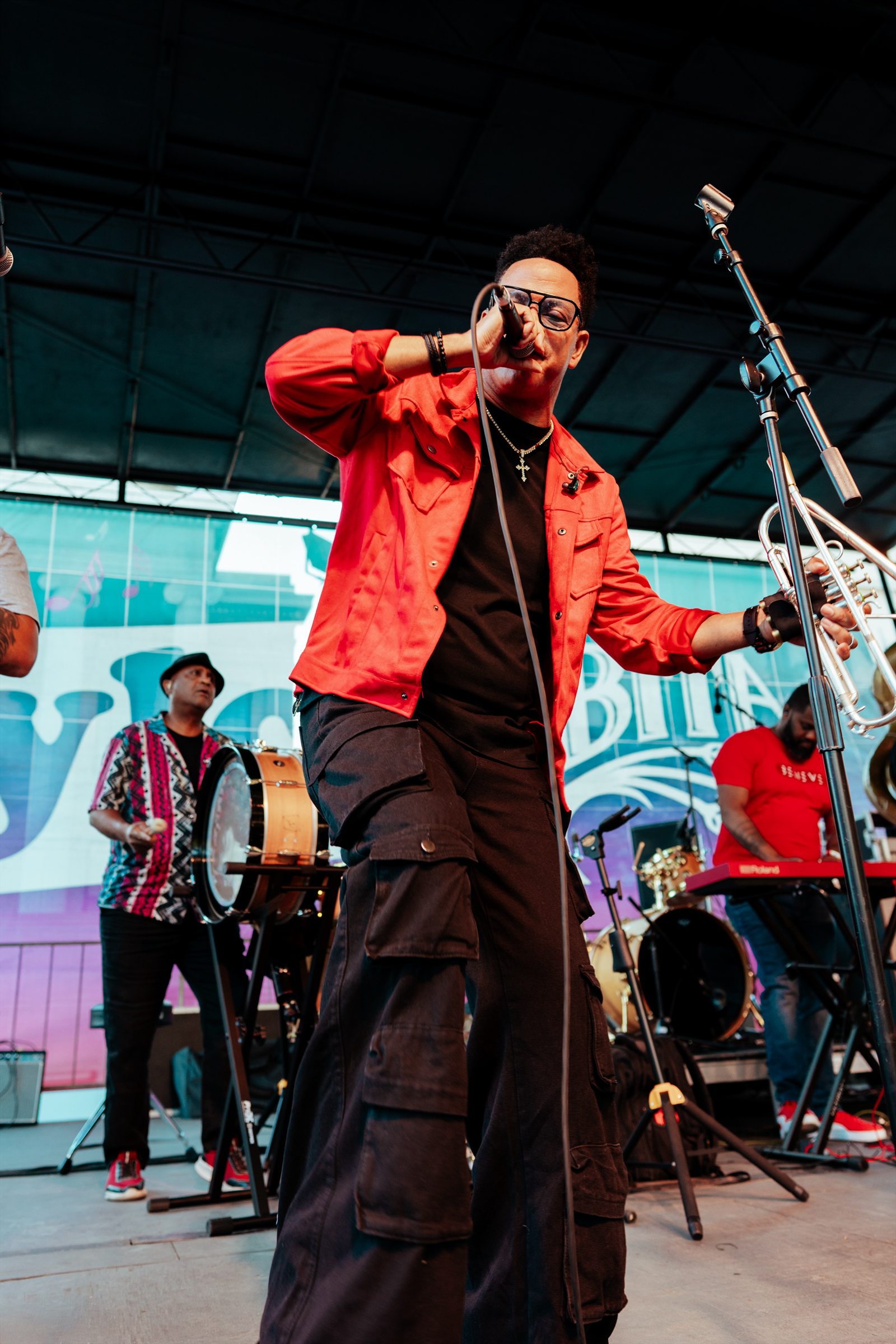 Brass musician in a red jacket performing at a large outdoor event